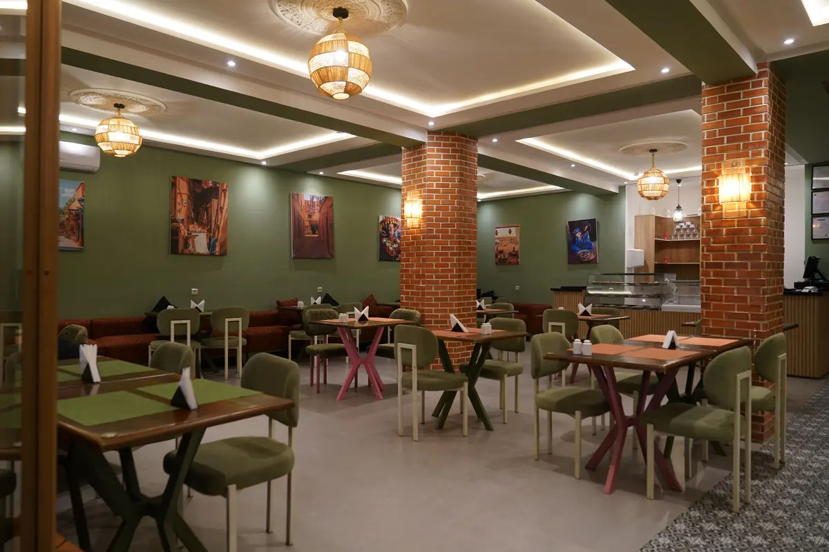 Main dining room with brick columns, sage chairs and Moroccan artwork