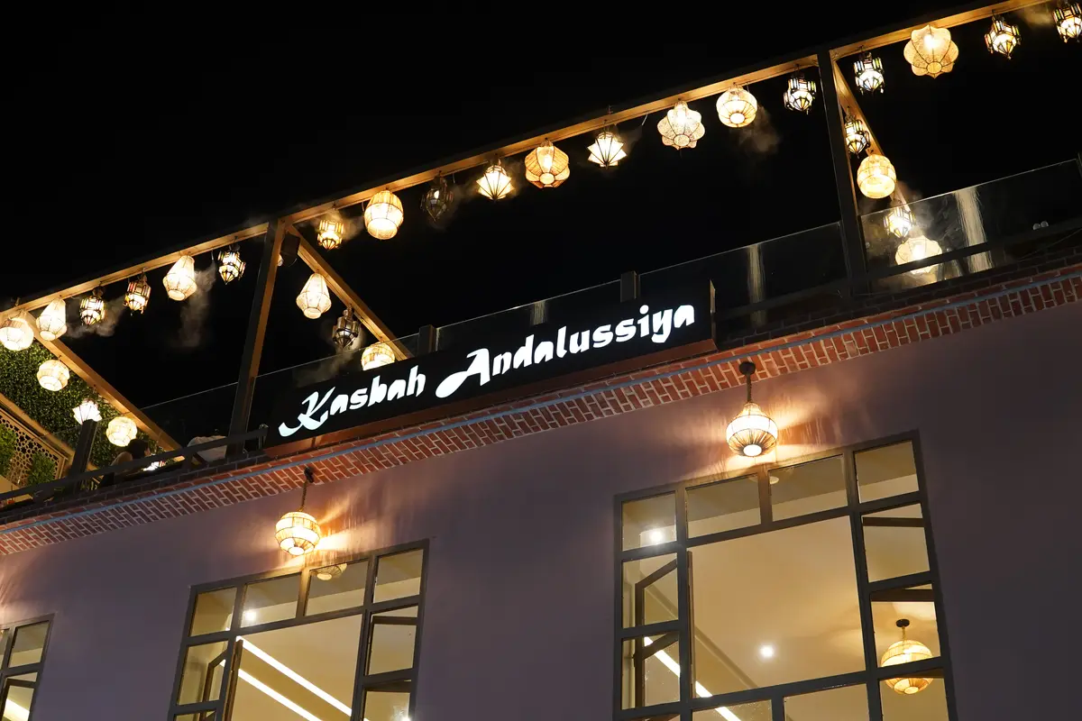 Illuminated Kasbah Andalussiya sign beneath rooftop lights at night