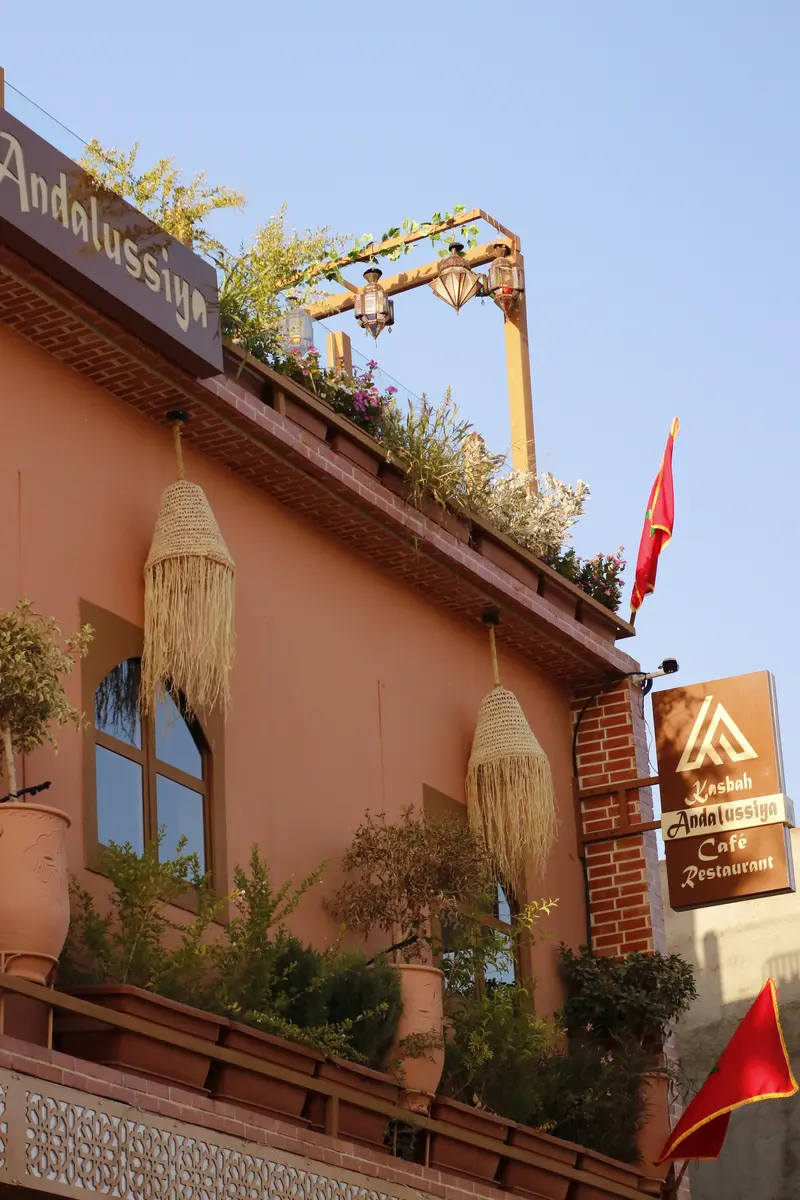 Terracotta walls, balconies and the Moroccan flag against a blue sky