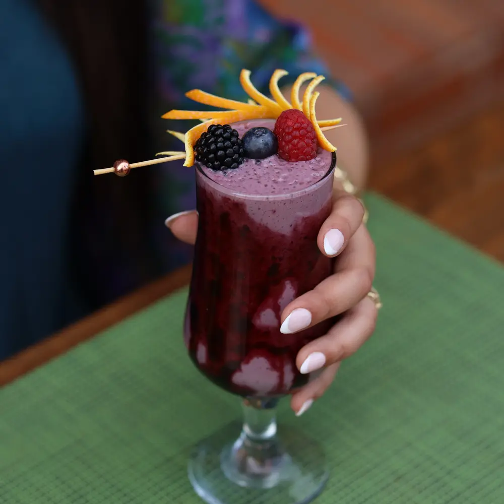 Berry smoothie garnished with orange zest and fresh fruit